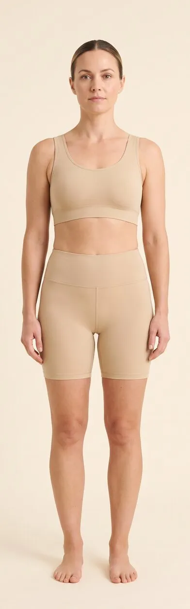 Body. Full-length front-facing photograph of a woman standing in plain activewear, used as a reference plate for the body areas the treatment reaches. Marked areas: 12 hyperhidrosis (excessive sweating).