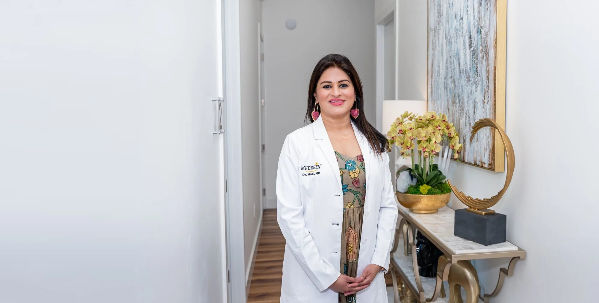 Dr. Haritha Mikkilineni, MD, in a lab coat in the corridor of the Medrein Health clinic in Southlake, TX