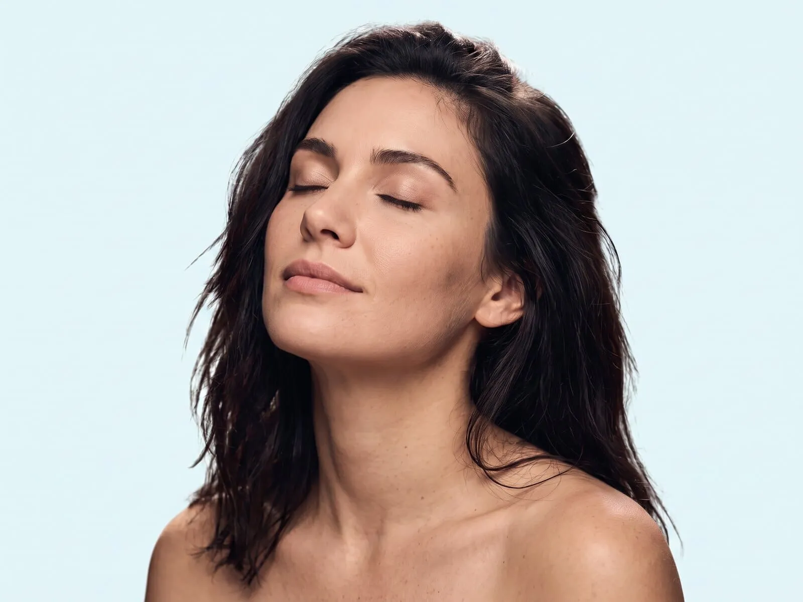Calm head-and-shoulders portrait of a woman with her eyes closed and her face lifted to the light, the facial skin Comfortlase light therapy supports