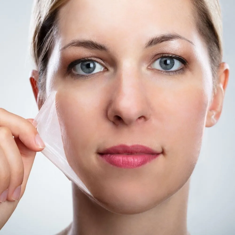 A woman lifting a translucent exfoliated layer away from her cheek after a chemical peel treatment