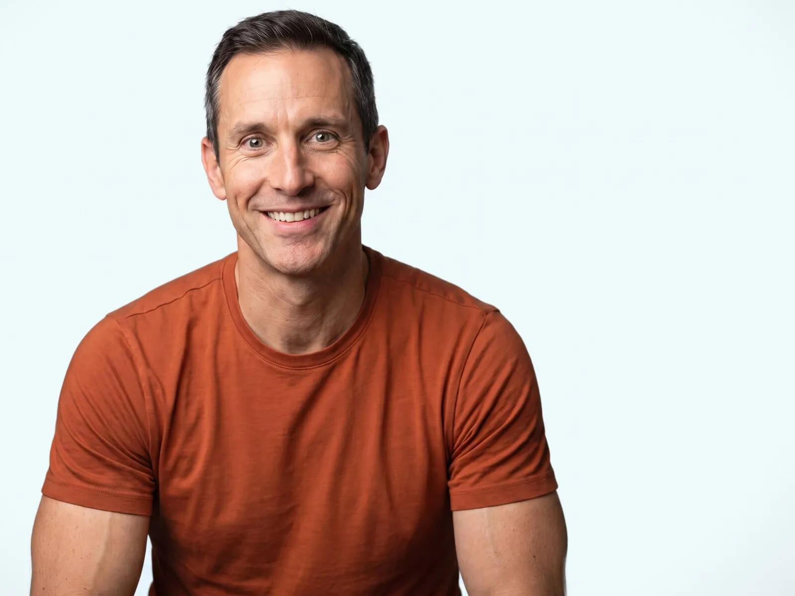 A lean, athletically built man in his forties, shoulders and upper arms in frame, the area testosterone therapy acts on