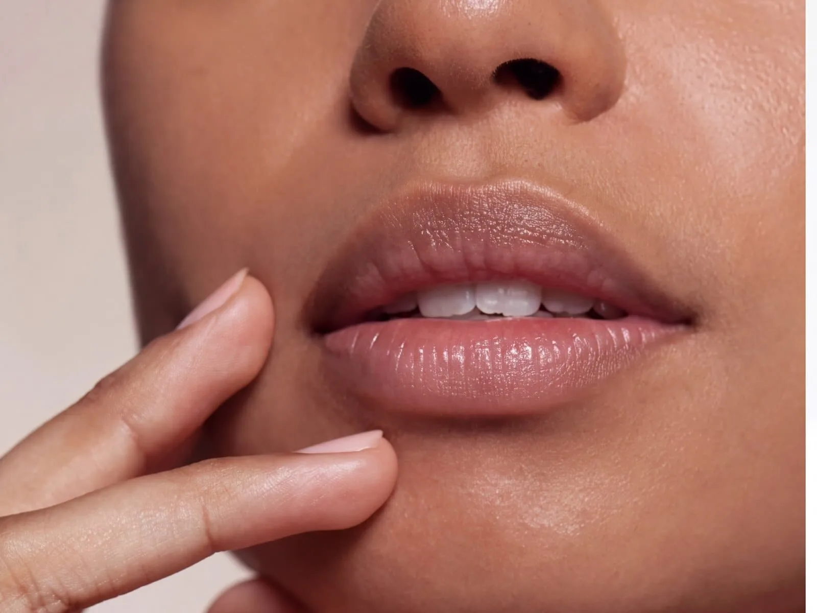 Close view of a woman's naturally full, softly defined lips with her fingertips resting at her chin, the shape LipLase builds from your own collagen